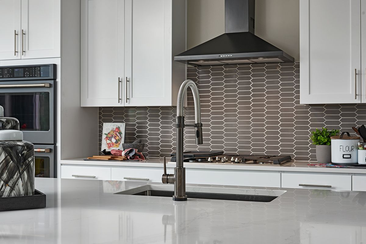 Kitchen island in front of wall of cabinets with picket backsplash and gas stove