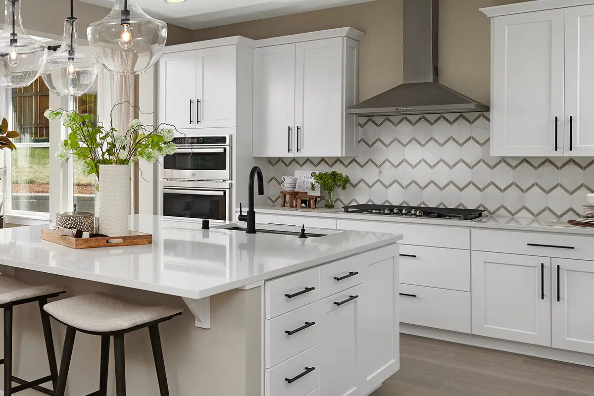Kitchen with white cabinets and white countertops, a large gas stove, and patterned backsplash