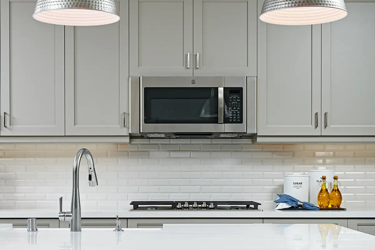 Upper cabinets with microwave above gas stove and brick-style backsplash