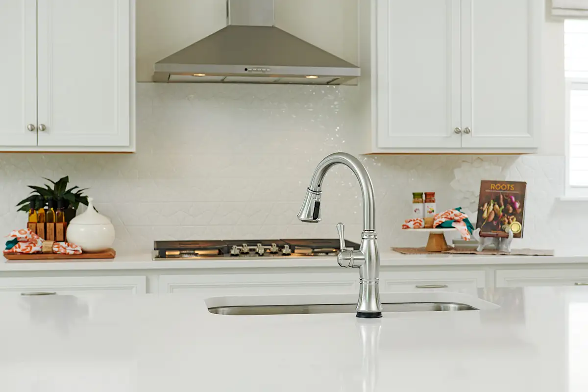 White island with silver faucet in front of gas stove and patterned backsplash
