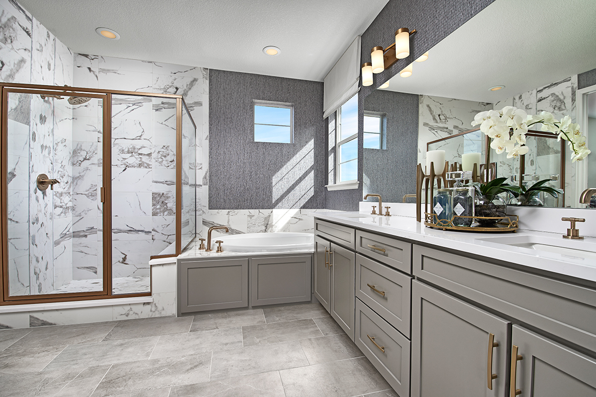 Large bathroom with double sinks, bathtub, striped wallpaper, and an open door leading into the owner's bedroom