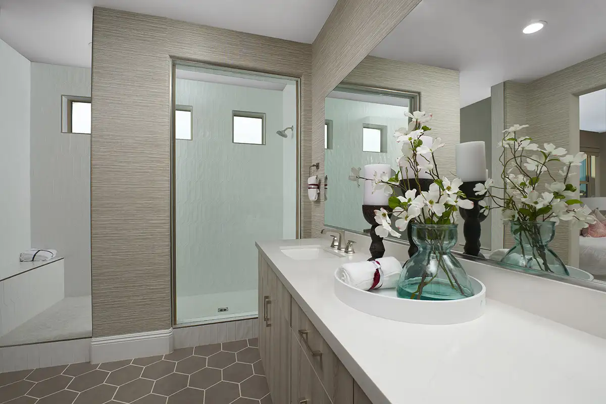 Bathroom vanity with double sink and large shower stall with three small windows and a seat