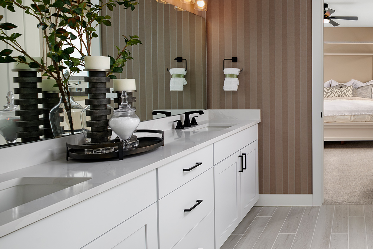White bathroom vanity with two sinks below large mirror and striped wallpaper