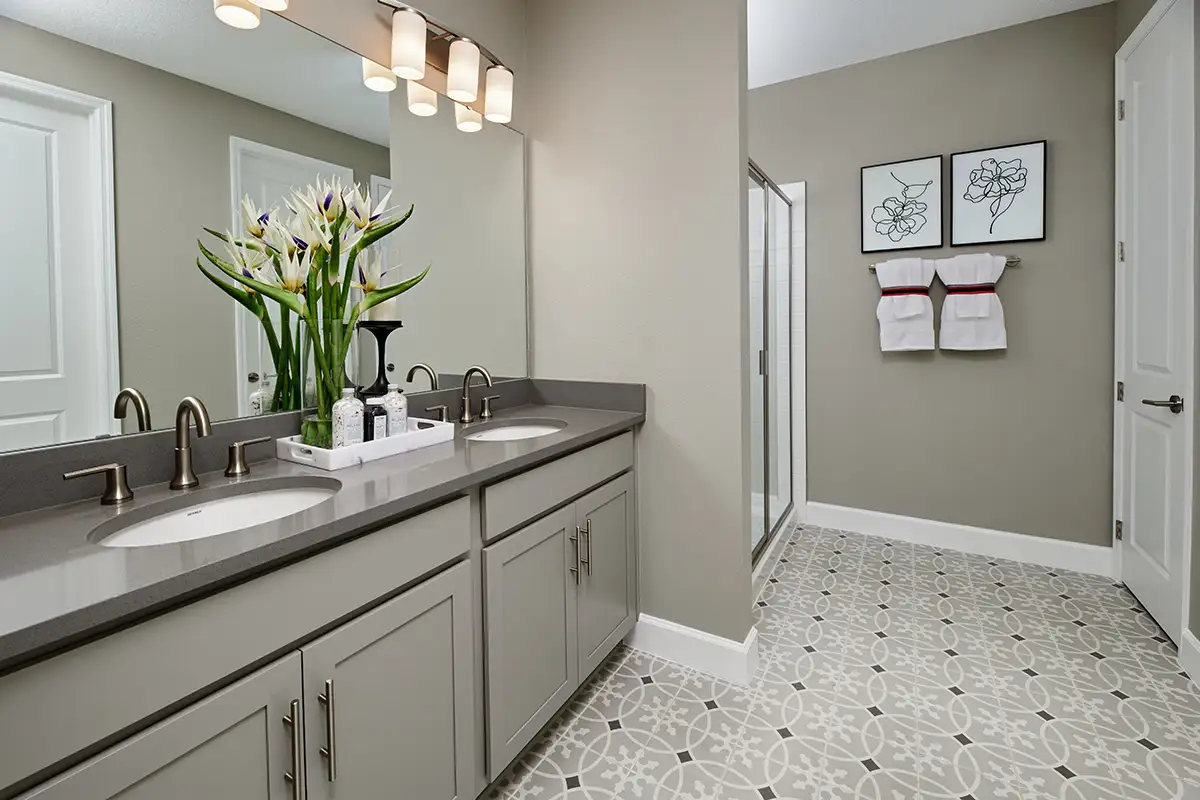 Bathroom with patterned tile, double sink, and shower stall