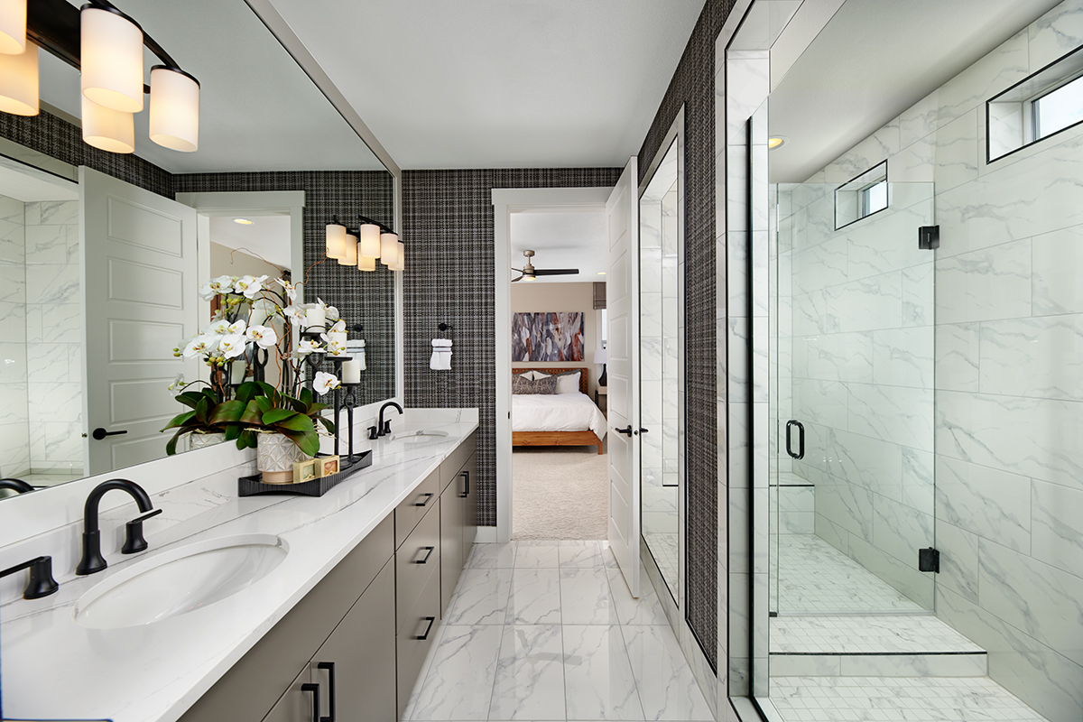 Large vanity with double sinks and light countertops and large shower stall with seat