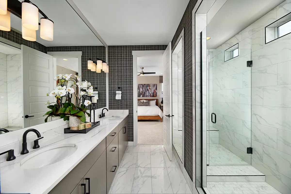 Large vanity with double sinks and light countertops and large shower stall with seat