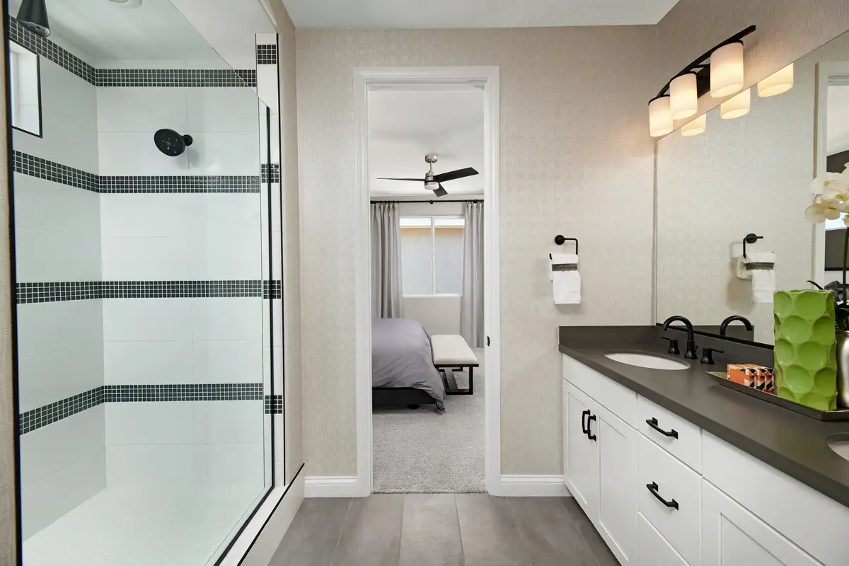 Bathroom with large double vanity with white cabinets and a dark countertop, and a shower stall with patterned tile