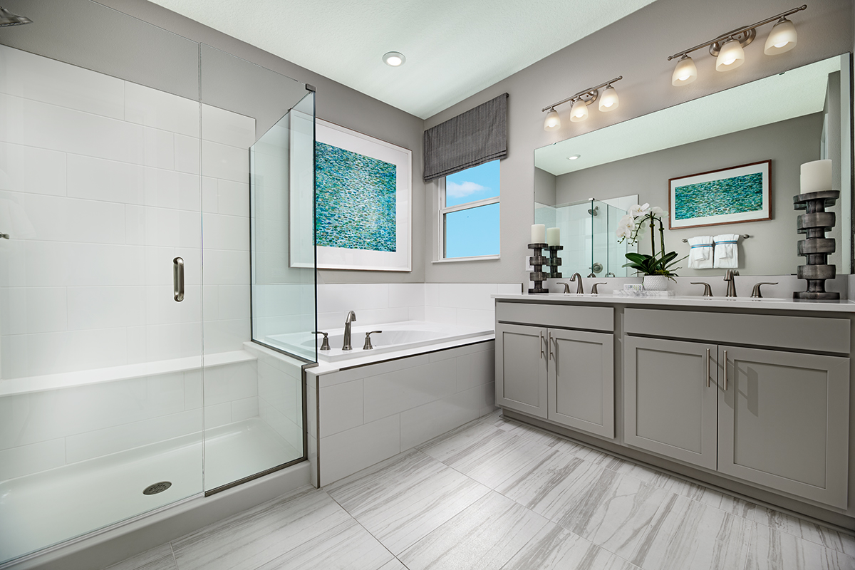Large bathroom with double sink vanity, bathtub next to window, and shower stall