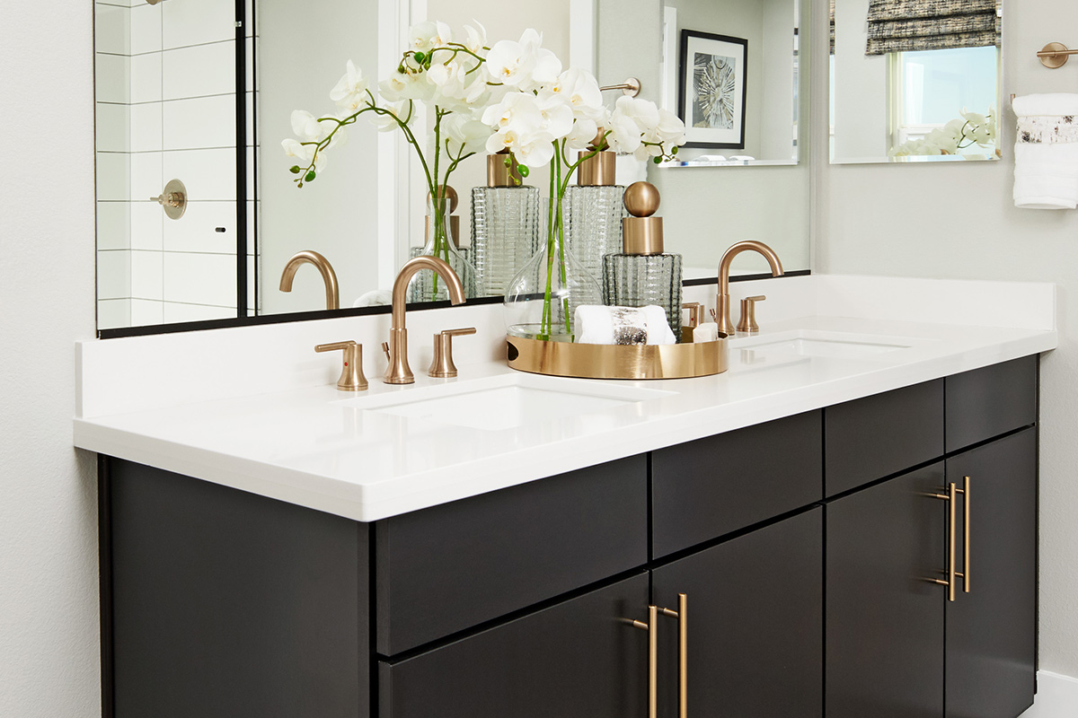 Black-cabinet vanity with white countertops, two sinks, and gold hardware